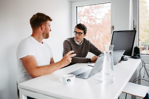 Zwei uppr-Mitarbeiter sitzen vor ihren Laptops und unterhalten sich