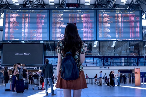 Eine Influencerin steht vor einer Anzeigetafel im Flughafen-Terminal - ein Symbol für Reisen und Affiliate-Marketing-Programme.