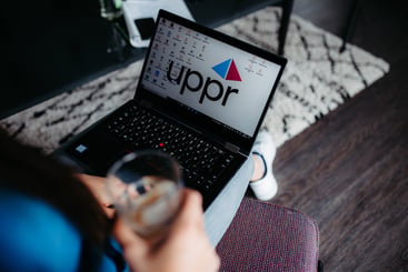 Eine Frau sitzt vor dem Laptop und trinkt Kaffee. Die KI-Kennzeichnungspflicht betrifft auch Affiliate-Marketing-Agenturen wie uppr.