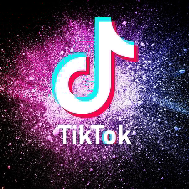 Das Bild zeigt das Logo von TikTok vor einem dynamischen, bunten Hintergrund aus pinken, violetten und blauen Farbspritzern.